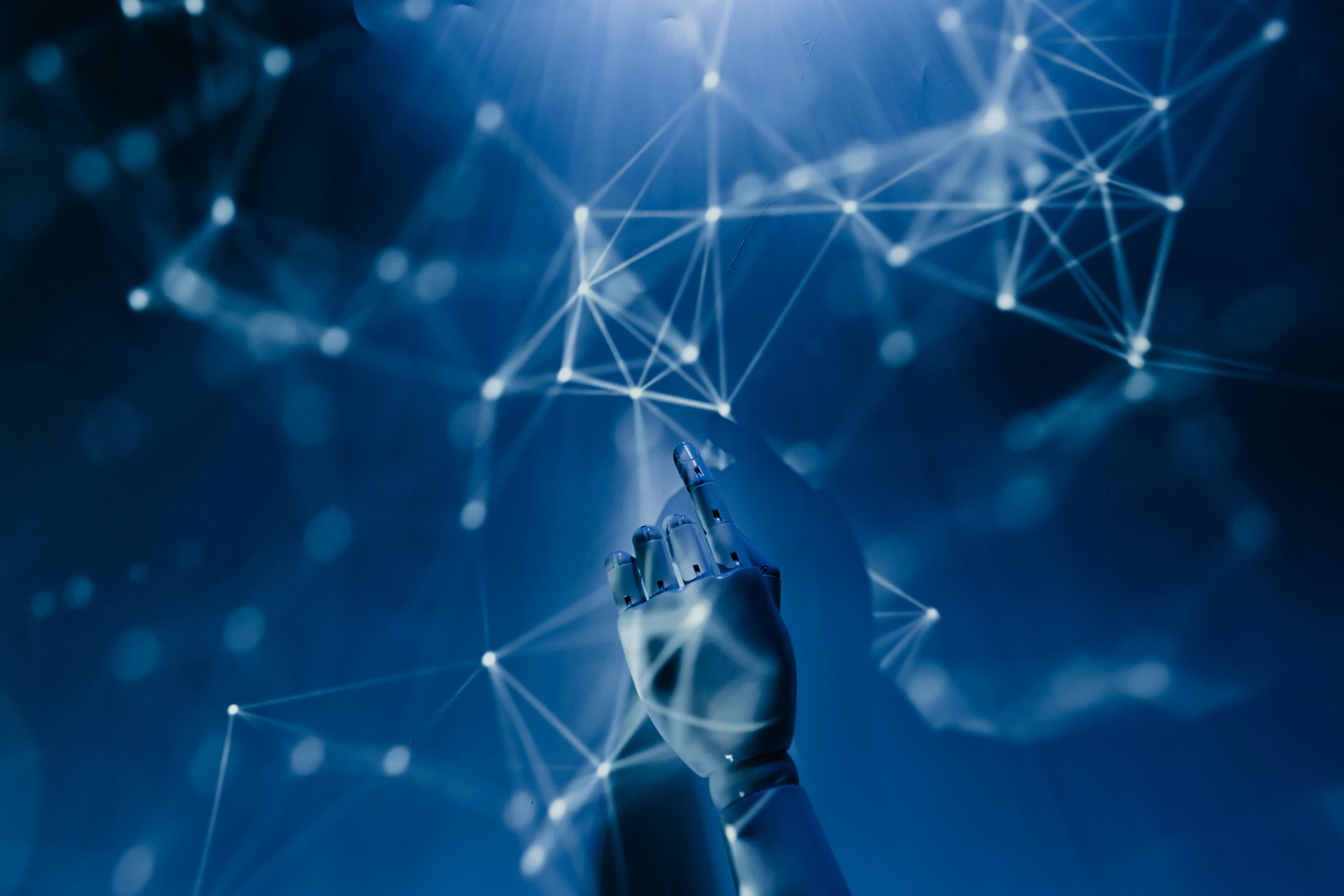 Robotic hand reaching toward a glowing AI neural network mesh on a deep blue background