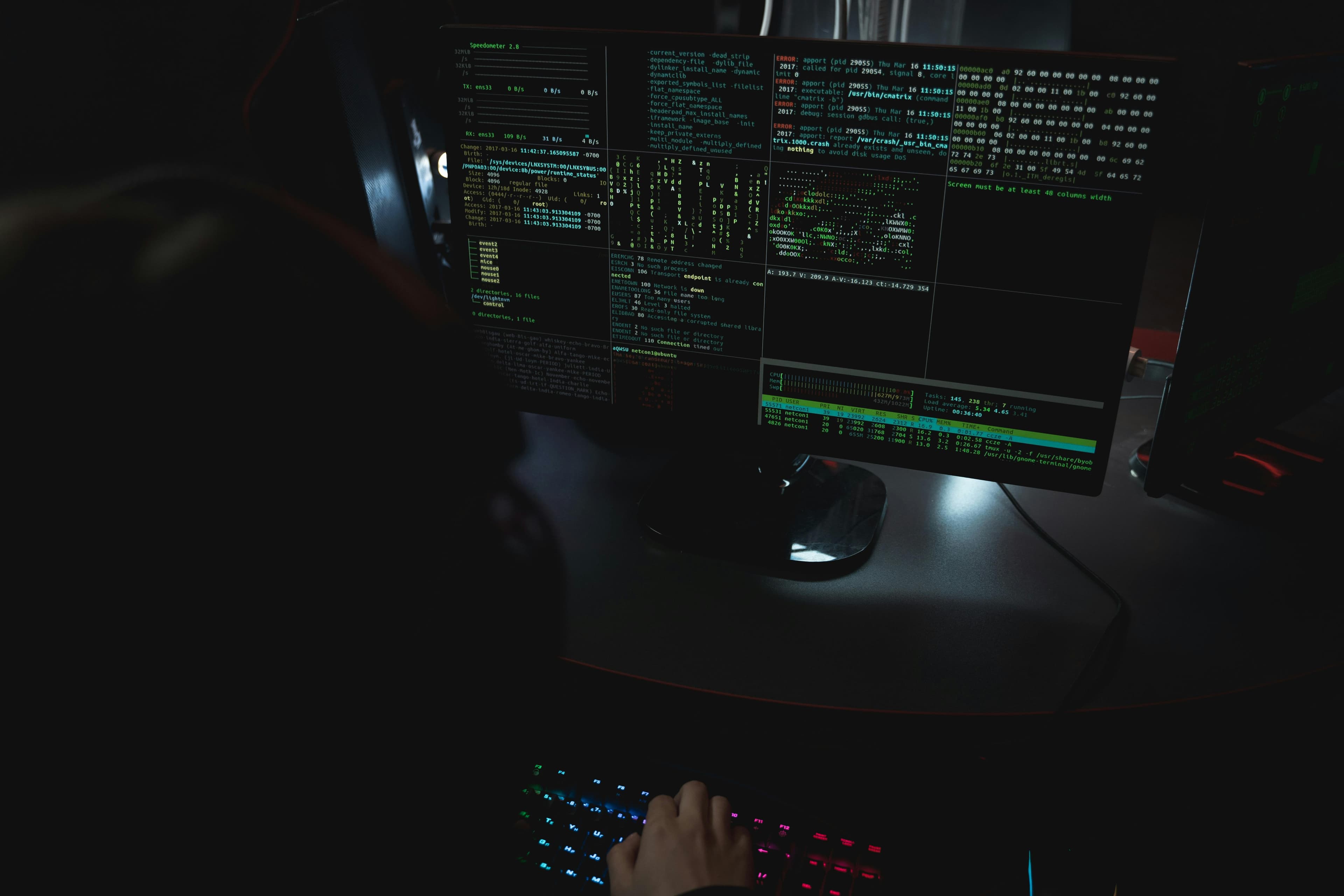 Security analyst monitoring live threat logs and system activity on multiple screens