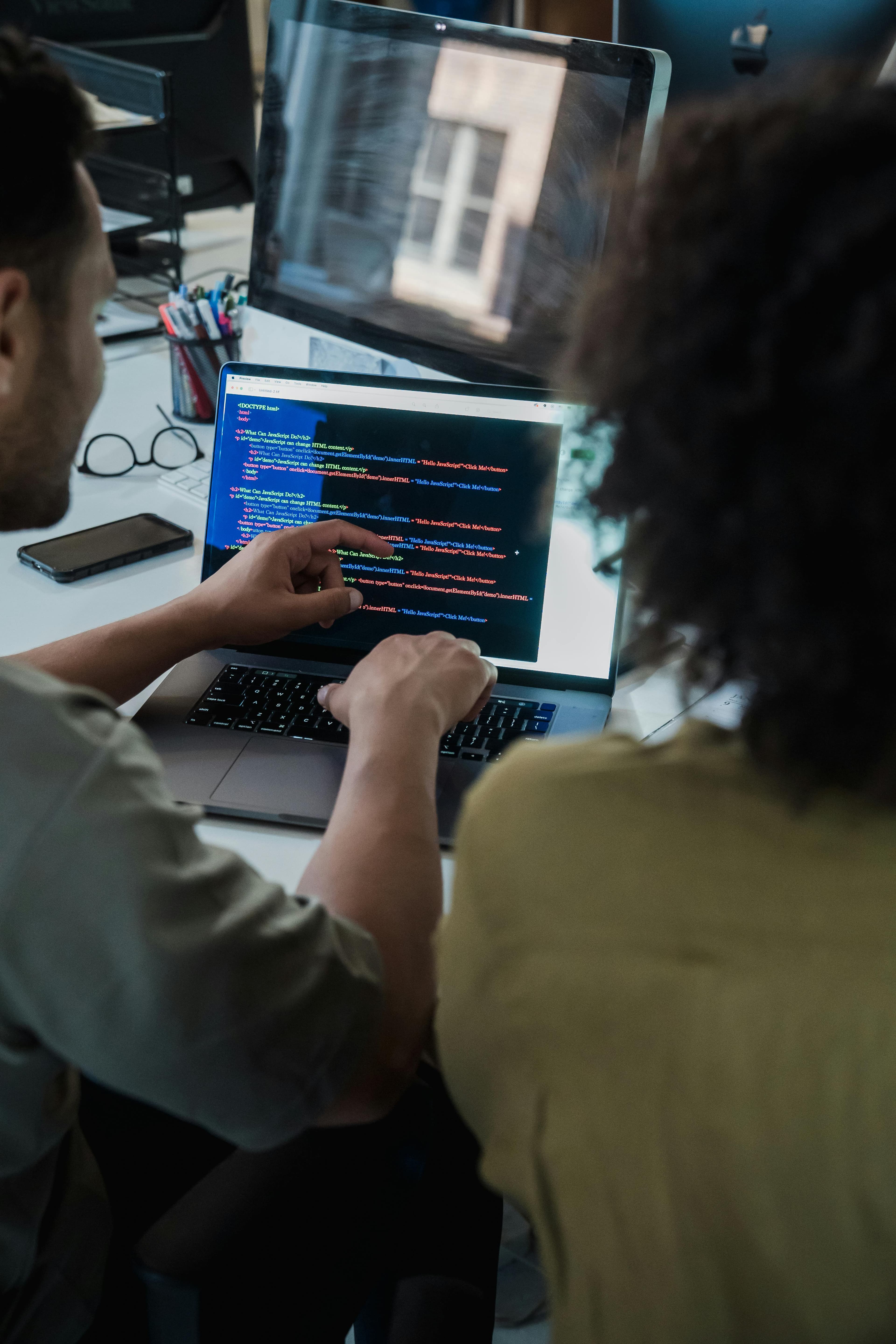 Two software developers reviewing application code together on a laptop