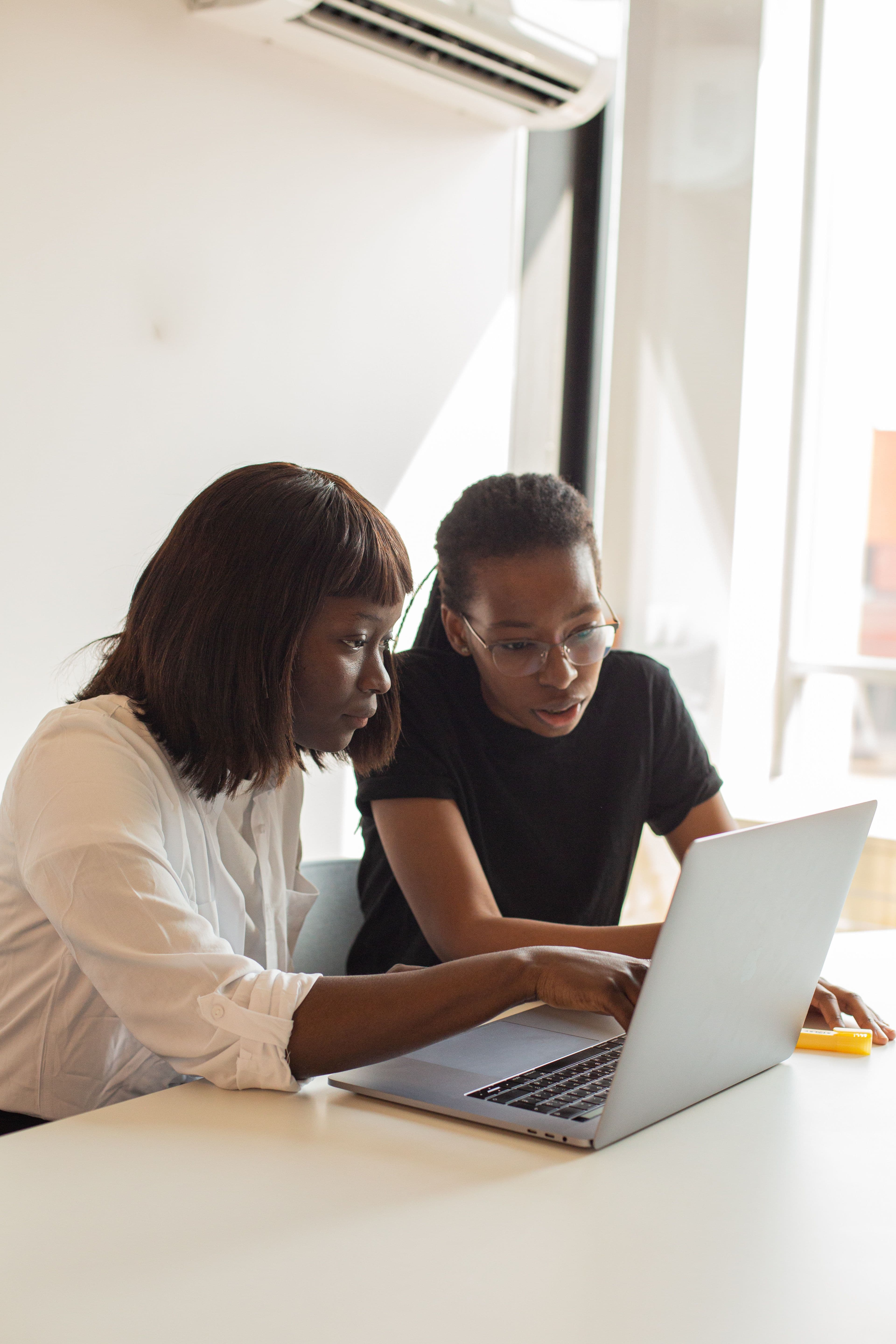 Two Mectrack team members collaborating over a laptop in a bright office